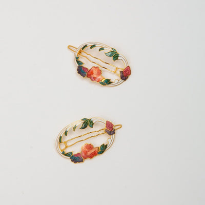 Pair of hair clips that are white with colorful flowers.