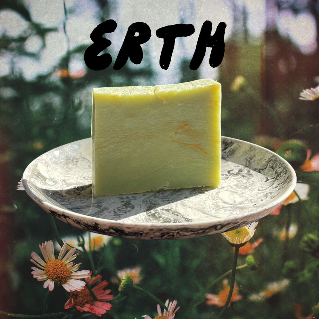 East West Shop x Iron Lion Soap -green Erth Bar - sitting on a plate in front of calendula flowers.