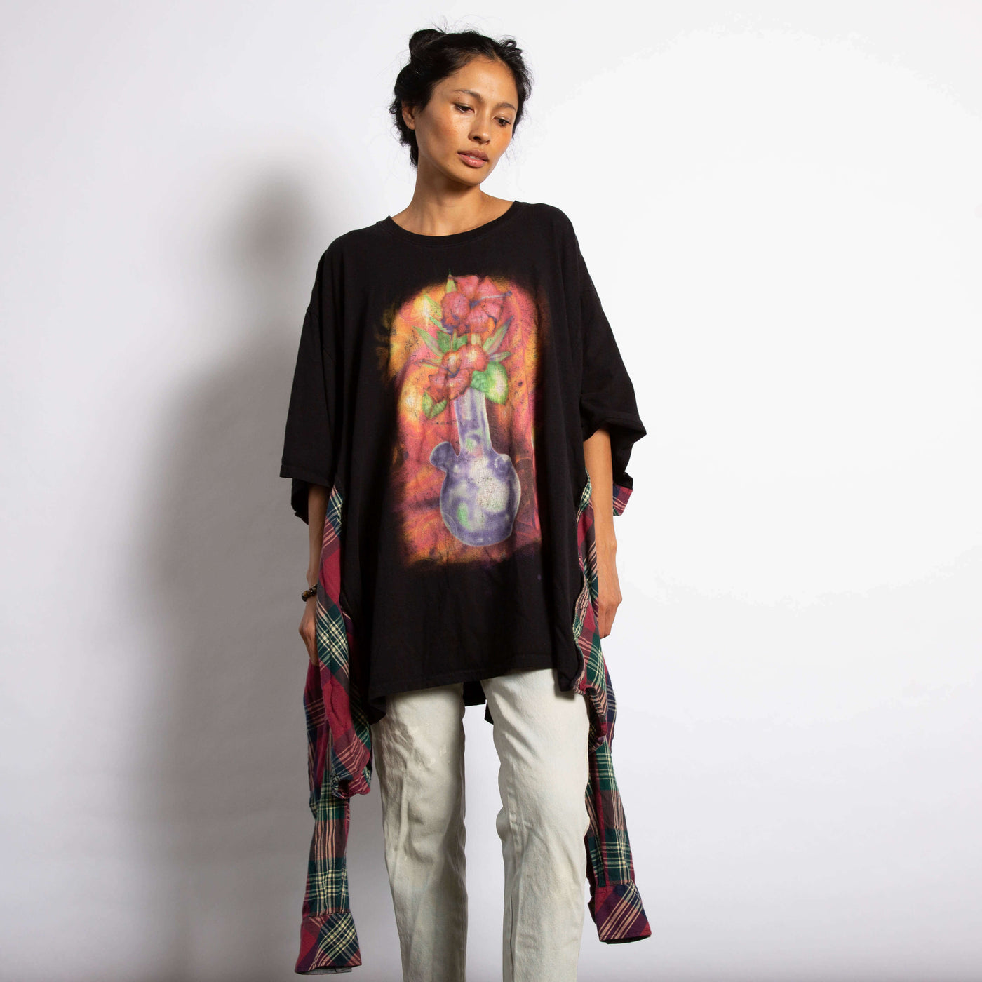 Model is wearing an oversized black Tee with a graphic of a glass bong with flowers.  On the sides of the tee the sides of a flannel shirt are sewn on