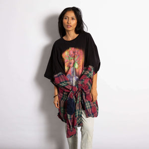 Model is wearing an oversized black Tee with a graphic of a glass bong with flowers. On the sides of the tee the sides of a flannel shirt are sewn on.  Sleeves are tied together at the waist.