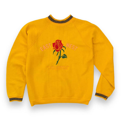 Bright yellow sweatshirt with detailed collar and wrist bands on white background. The sweatshirt has a red rose embroidered on the center. To the left of the rose it says “EAST” and to the right it says “WEST” under the rose reads “ 727 NORTH BROADWAY #115 LOS ANGELES, CA 90012” all in pink text.