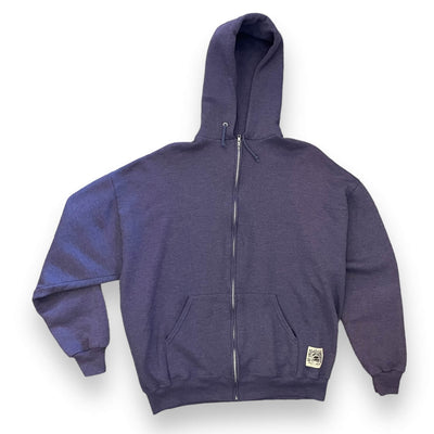 Image of a purpley grey zip up hoodie on white background. The zip up has a small square patch on the right pockets bottom corner. The patch has a woodblock style graphic, of a turtle with a peace sign on its shell wearing a top hat with the sun shining behind it. It reads “ RE-ENERGIZED RECYCLED, EAST / WEST, LOS ANGELES”