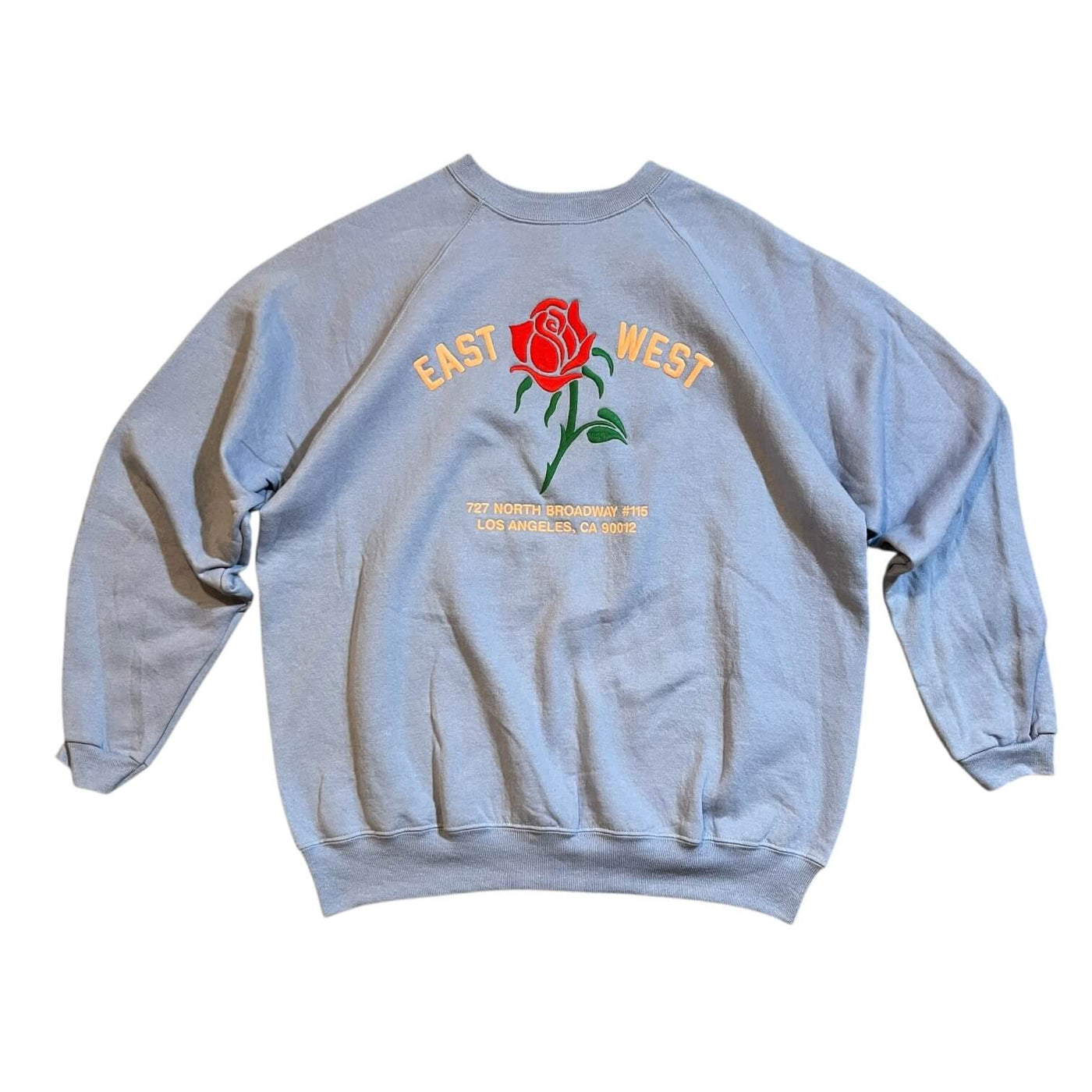 Light Blue sweatshirt with a red rose and text design on a white background