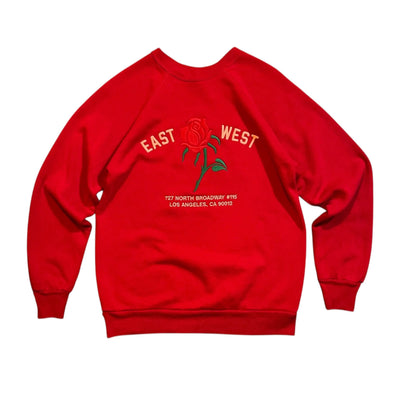 Red sweatshirt with 'East West' text and rose graphic on a white background