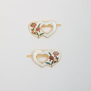 Pair of white hair clips in the shape of hearts.  With flower and butterfly design.