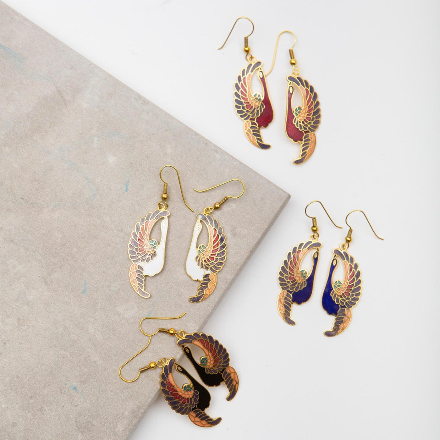 Cloisonné Earrings - Cranes all four colorways laying on a stone.