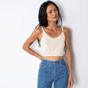 Jade is wearing a natural colored tank top with thin straps and elastic on the hem.  Worn with high waisted denim.