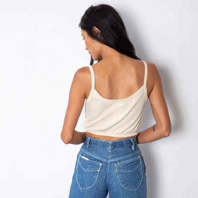 Jade is wearing a natural colored tank top with thin straps and elastic on the hem.  Worn with high waisted denim.