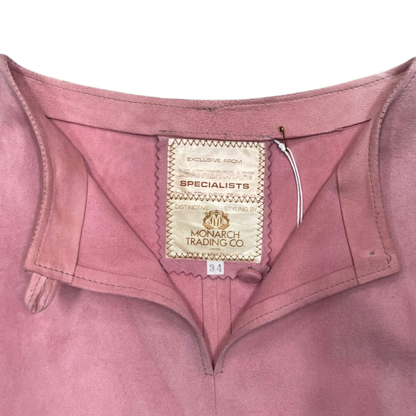 Pink suede top buttoned up at the neck.